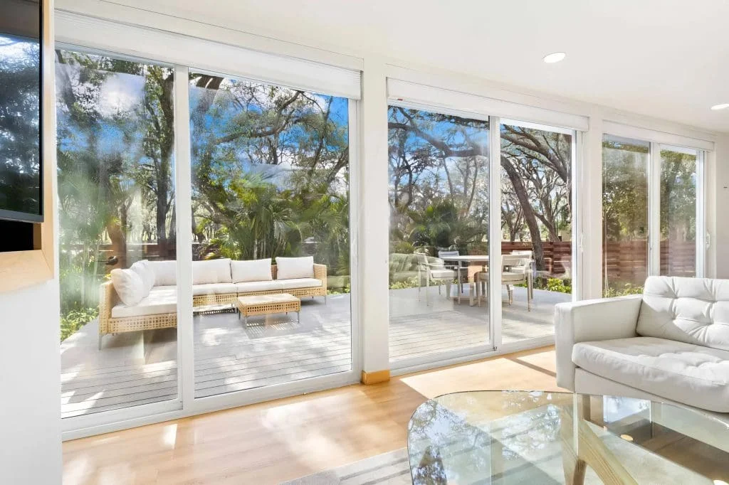 Living room with large glass doors opening to the outdoor deck and garden views