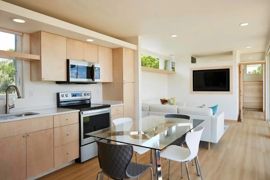 Open-concept kitchen, dining, and living area with natural light and modern design